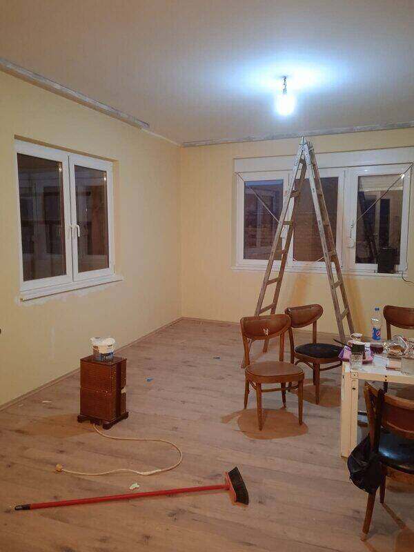 Merdevine,četka,sto i stolice u okrečenoj sobi